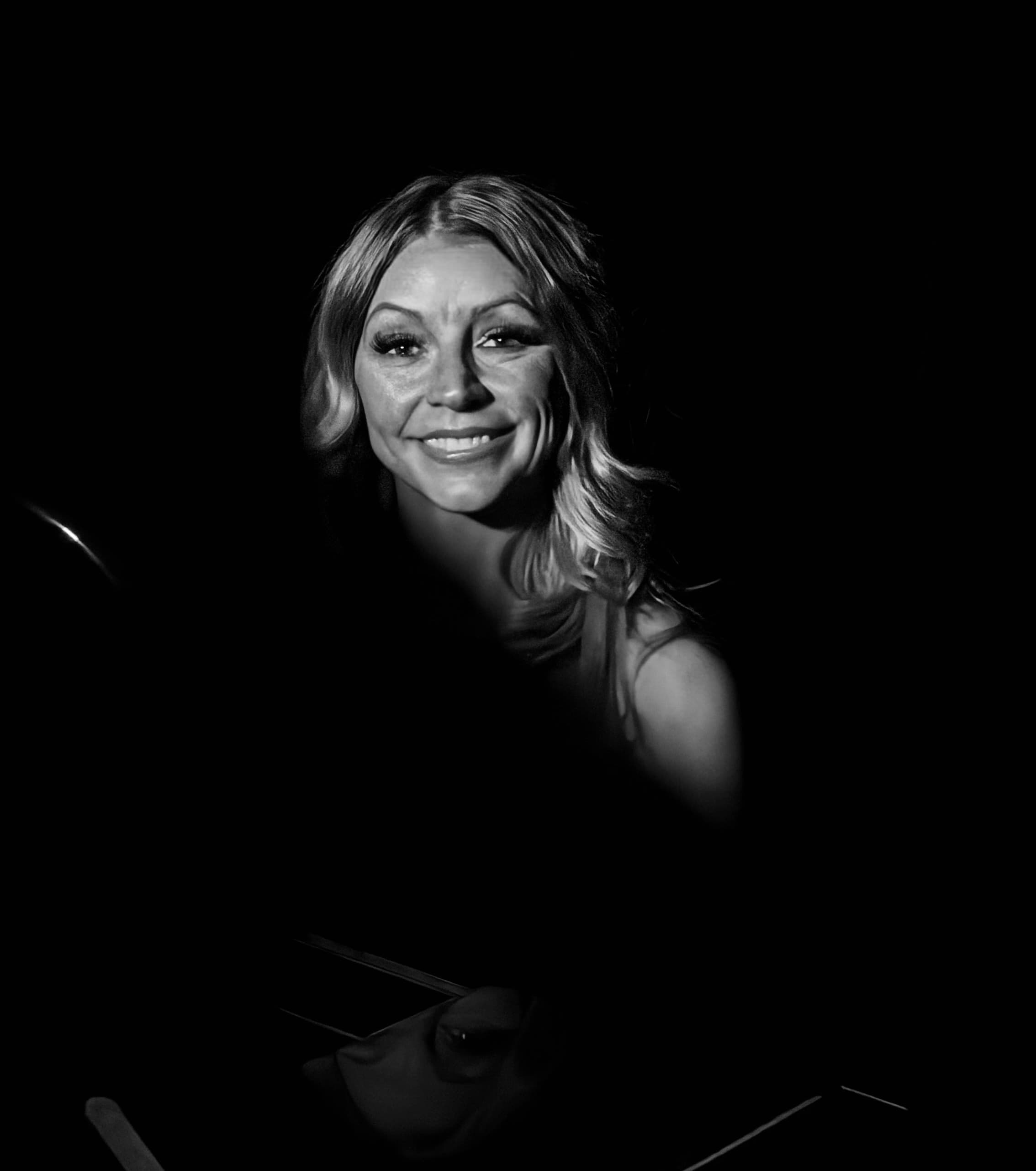 Lisa Apple smiling in dramatic black and white light