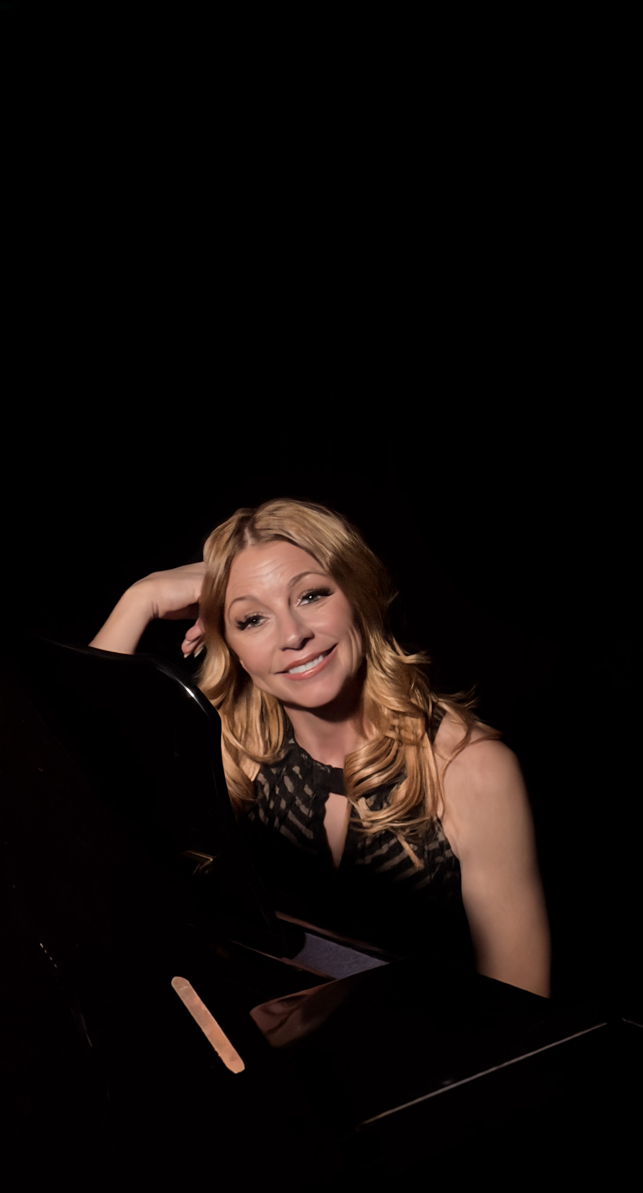 Lisa Apple at the piano — warm amber light, dark backdrop